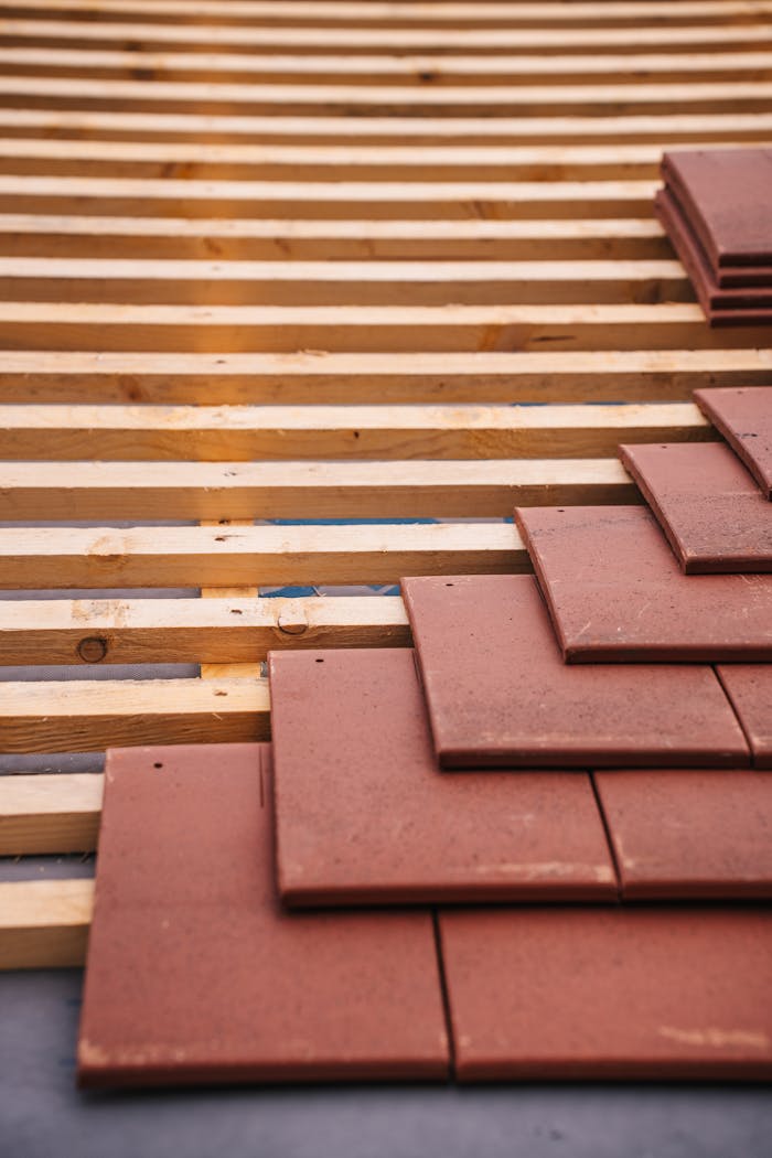 Services-03 Red roofing tiles and wooden framework in progress on a building roof.